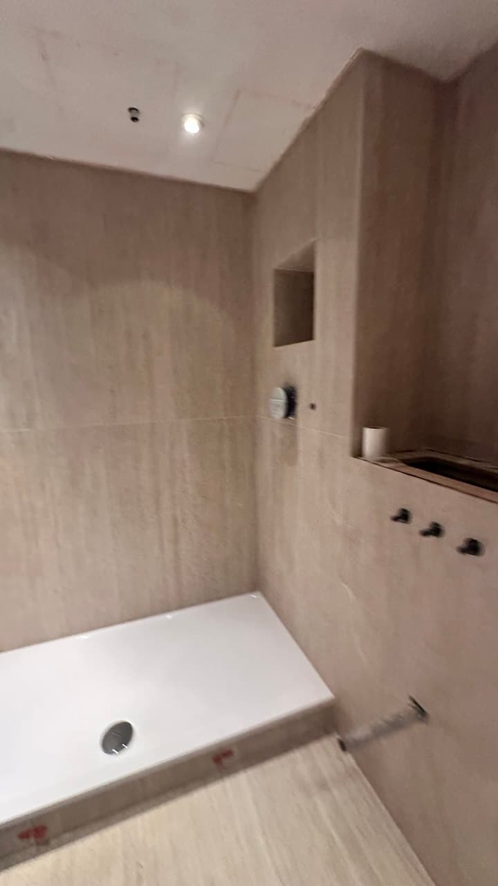 En-suite marble installation in progress with service positions set out