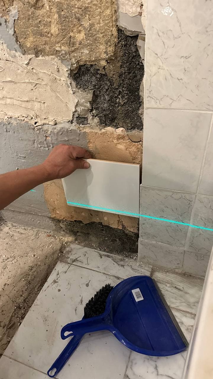 White wall tiles being set out using a laser level