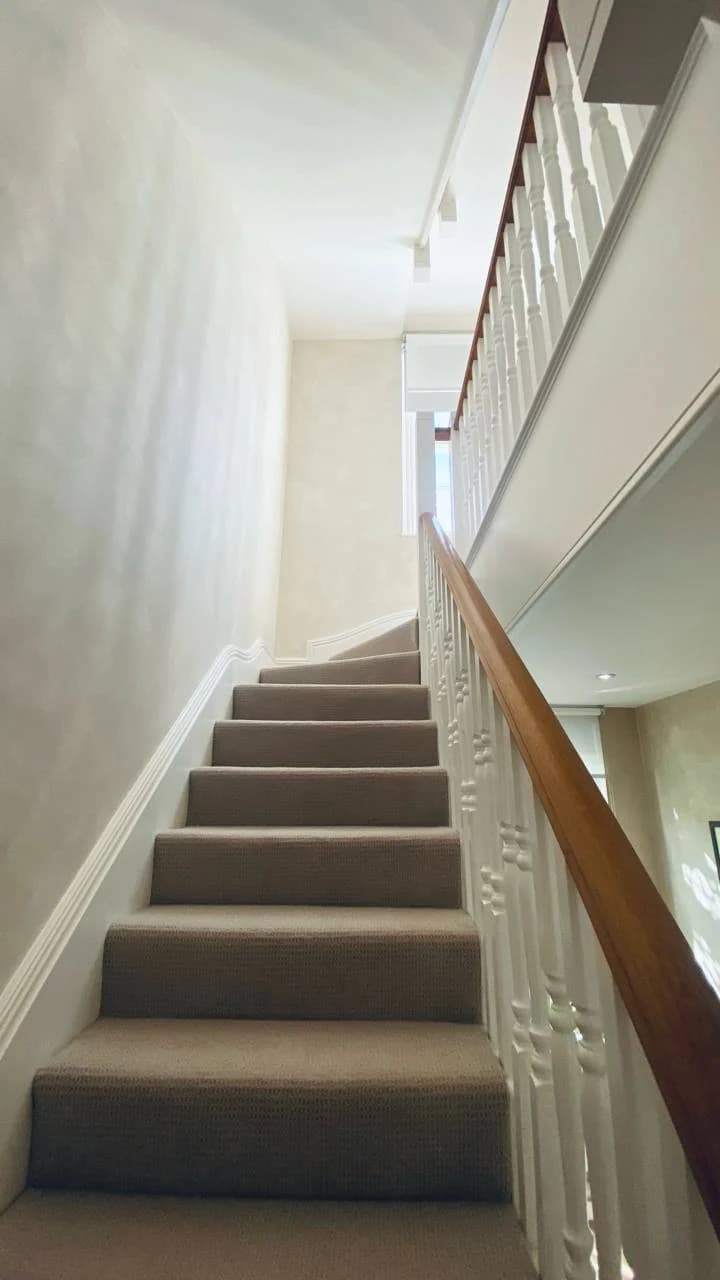 Carpeted staircase framed by white spindles and a polished timber handrail