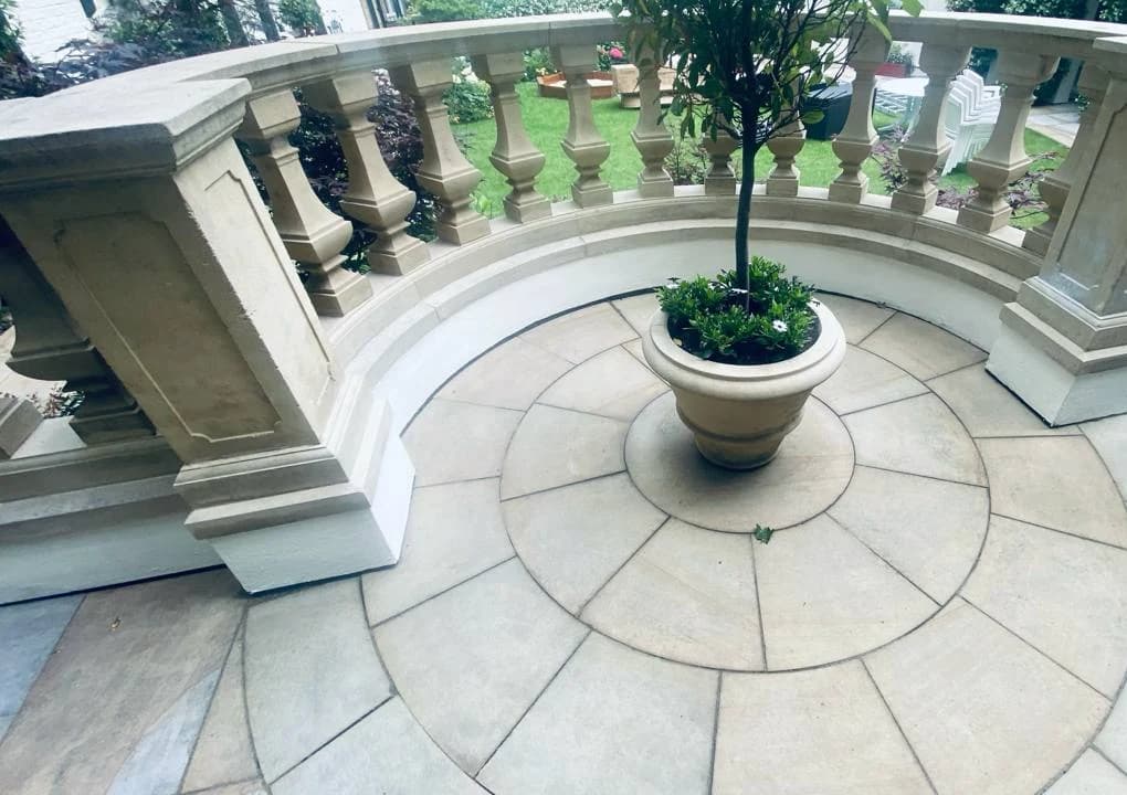 Curved stone terrace and balustrade arranged around a central planter